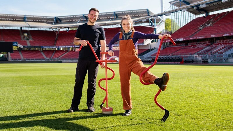 Marina hilft Greenkeeper Stefan den Fußballplatz im Stadion auszubessern. – Bild: BR/​megaherz GmbH/​Hans-Florian Hopfner