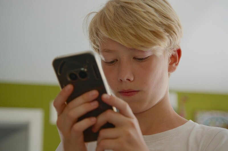 NZZ Format Aufwachsen ohne Smartphone – Ist eine Kindheit ohne Tiktok und Co. möglich? John mit Smartphone – Bild: SRF/​NZZ Format