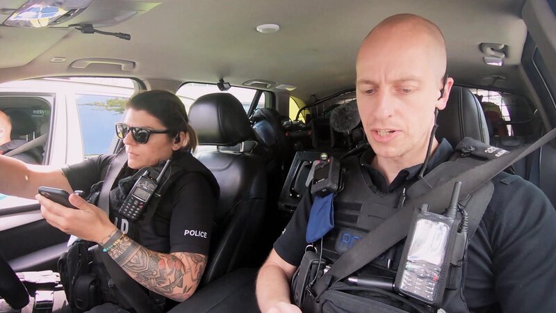 Polizeibeamte in einem Auto. Lisa Desantis (l.) und Gavin Hall (r.) – Bild: Warner Bros. Discovery