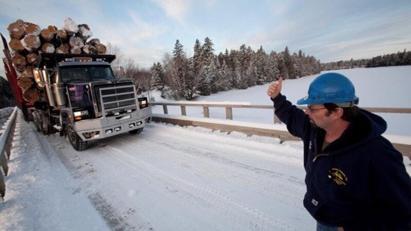 Rudy Pelletier (in blue sweatshirt) and a logging truck with 275,000 pounds of timber driven by Lester Dube on a worksite at the Pelletier’s vast logging operation in Northern Maine. – Bild: Discovery Communications LLC.