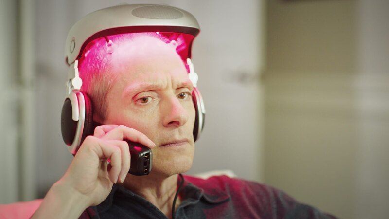 Ashley talking on his cellphone will wearing his hair growing machine on his head. – Bild: Discovery Communications, LLC.