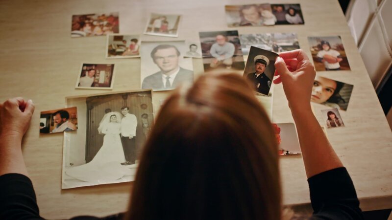 A portrait of Lori Orr-Kovach looking at old photos of her Dad John Orr. – Bild: Discovery Communications, LLC
