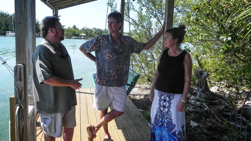 Realtor, Brett Newman (L) talking with the homebuyers, Buck (C) and Rosie Donnelly (R) on the dock of the first home. – Bild: HGTV
