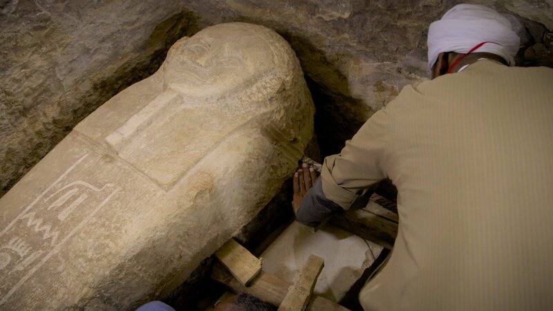 Der leitende Vorarbeiter des Ausgrabungsteams von Saqqara, Rais Ammar, hebt den Deckel des Sarkophags des Priesters Ayput vorsichtig von seinem Sockel. Obwohl es sich um den einzigen anthropoiden (menschenförmigen) Deckel des Komplexes handelt, ist er auch der leichteste, d. h. seine Entfernung ist mit der Kraft von drei Personen möglich. – Bild: National Geographic /​ Will Churchill