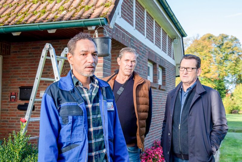 Khalid Hadam (Raschid Daniel Sidgi, l.) erfährt durch Finn (Sven Martinek, M.) und Lars (Ingo Naujoks, r.) vom Tod seiner Frau. Er ist sichtlich mitgenommen. – Bild: ORF/​ONE GATE/​ARD/​Thorsten Jander