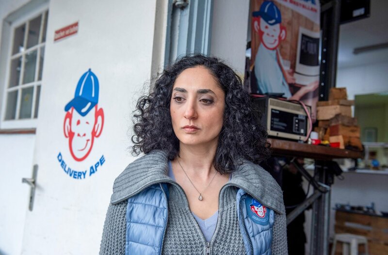 Yeliz Bulut (Ariella Hirshfeld), die Chefin von „Delivery Ape“ beobachtet mit ernstem Blick den Disput zwischen Adrian und Pablo. – Bild: ORF/​ONE GATE/​ARD/​Thorsten Jander