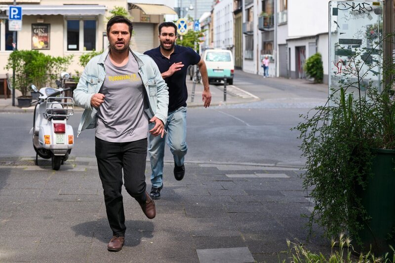 Paco (Milos Vukovic, l.) will panisch verhindern, dass Britta wegen der Turnhalle ihre Gesundheit riskiert. Hinten Baris (Metehan Demiröz) – Bild: RTL /​ Stefan Behrens