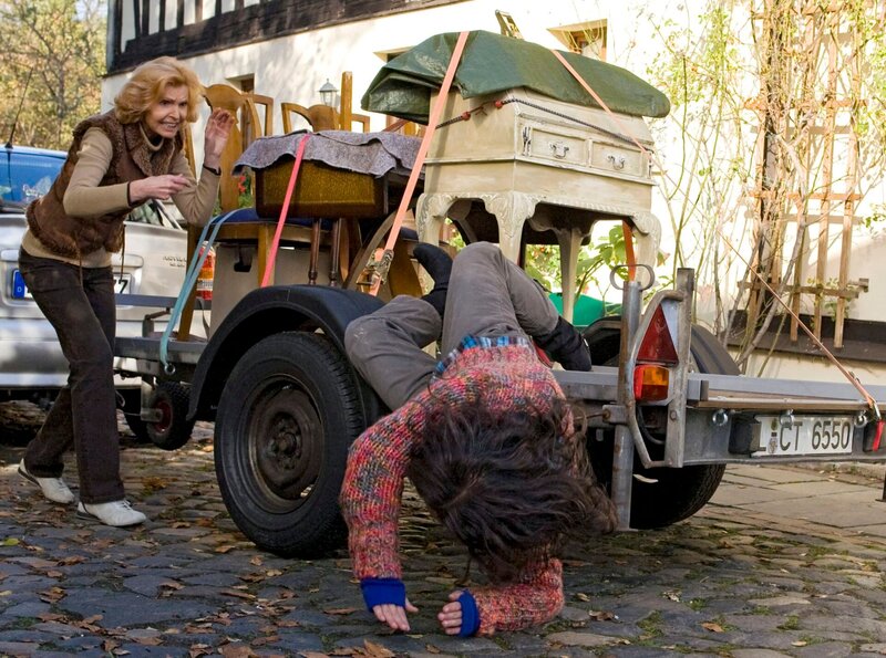 Ingrid (Jutta Kammann, links) bekommt von Marianne Maisenbacher (Anja Topf, fallend) einen alten Sekretär geliefert, den sie selbst abbeizen will. Doch beim Abladen des Sekretärs hat Marianne einen schweren Unfall. – Bild: MDR/​MDR/​Peter Krajewsky