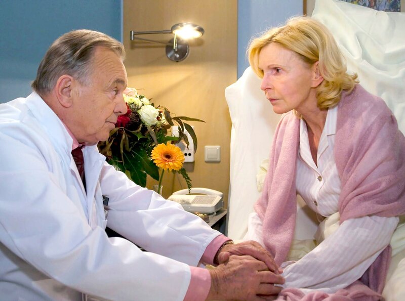 Prof. Simoni (Dieter Bellmann) sagt Ingrid (Jutta Kammann), dass sie nicht mit einer Therapie beginnen können, solange sie nicht wissen, wo der Primärtumor sitzt. Nach einem kurzen Schock, signalisiert die Oberschwester Kämpfergeist – sie wird nicht so leicht aufgeben. – Bild: „