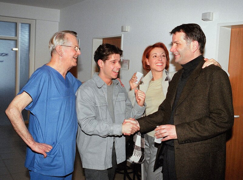 Roland Heilmann (Thomas Rühmann, re.) gratuliert Vladi (Stephen Dürr, 2. v. l.) zu seinem Baby. Auch Pia (Hendrikje Fitz, 2. v. re.) und Prof. Keller (Gert Gütschow, li.) sind überglücklich. Doch in die Freude über den kleinen Erdenbürger mischt sich Bestürzung, als Alina nicht aus der Narkose aufwacht. – Bild: MDR/​Laue