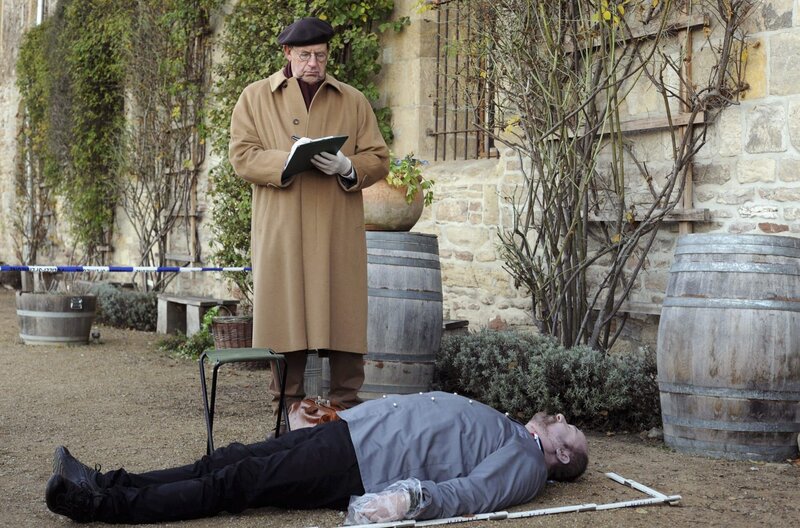 Dr. Münster (Jörg Gudzuhn, hinten) untersucht die Leiche des Chefkochs Dollberg (Jens Holger Lemke). – Bild: ARD/​BR/​Hardy Spitz