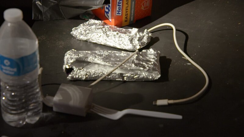 Zwei in Aluminiumfolie eingewickelte Telefone liegen auf einem Tisch in einem Versteck für geschmuggelte Menschen. – Bild: National Geographic