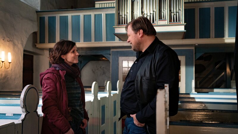 Überraschendes Wiedersehen macht Freude: Ina Behrendsen (Julia Brendler) trifft bei ihren Ermittlungen in der Kirchengemeinde auf Chorleiter Gero Lowitz (Michael A. Grimm). Erinnerungen an die gemeinsame Zeit in einer Rockband werden wach. Und Gero überzeugt Ina schnell davon, als Vorsängerin im Kirchenchor einzusteigen, denn seit dem Mord an Maria Fröbe ist diese Position vakant. – Bild: ZDF/​ Georges Pauly