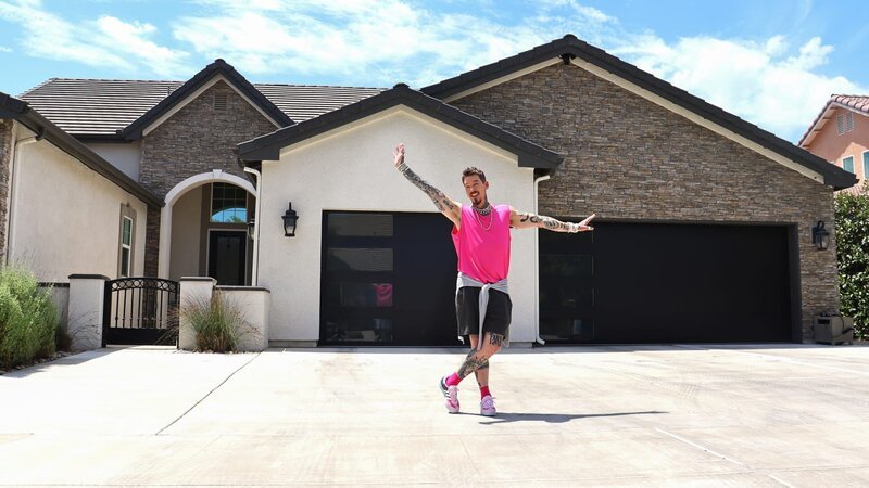 Host David Bromstad poses for a picture outside of House 1, Lupin Lane, as seen on My Lottery Dream Home, Season 17. – Bild: Warner Bros. Discovery