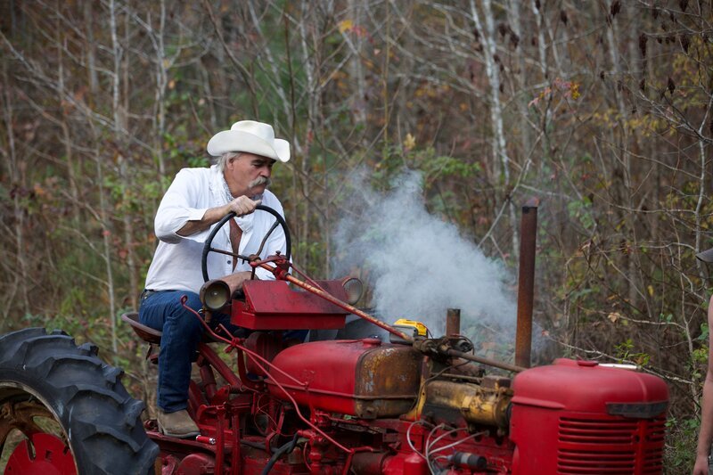 Marty Raney driving a red tractor. Smoke flows out of the side. – Bild: Warner Bros. Discovery, Inc. or its subsidiaries and affiliates