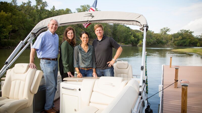 Portrait of Fixer Upper Hosts Chip and Joanna Gaines (R) with homeowners Allen and Gaile Holt (L) on the boat they arrived on for the reveal of their river-front home, as seen on Fixer Upper. – Bild: Sarah Wilson /​ Getty Images /​ HGTV /​ Scripps
