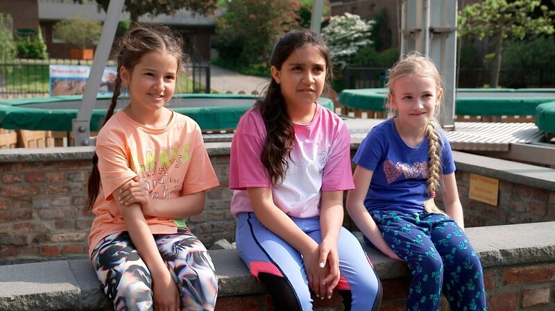 Nach dem ersten Teil des Langzeitprojekts „Kinder des Westens“ an Weihnachten 2021 und einem Wiedersehen mit den Kindern 2022 wollen wir auch im dritten Teil wissen, wie es ihnen geht, was sich seitdem verändert hat und was sie ganz aktuell beschäftigt. – Amal (l) mit ihren besten Freundinnen Zane (M) und Lia (r) im Interview. – Bild: WDR/​Brot&Butter ENTERTAINMENT