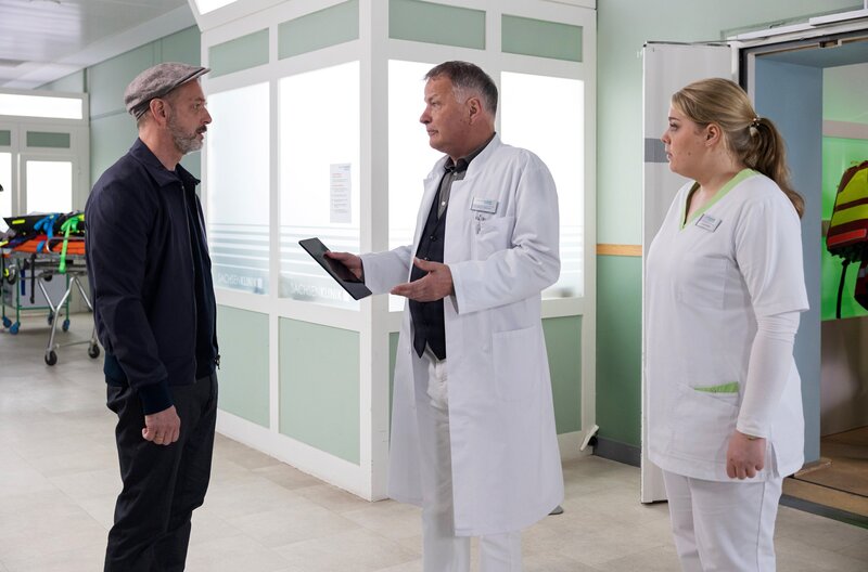 Silvio Vollinger (Martin Ontrop, li.) erkundigt sich besorgt nach seiner Frau, die nach einem schweren Autounfall in die Sachsenklinik eingeliefert wurde. Ihr Zustand ist äußerst kritisch und Dr. Roland Heilmann (Thomas Rühmann, mi.) muss sie operieren. Er bittet Schwester Miriam (Christina Petersen, re.), sich um Herrn Vollinger zu kümmern. – Bild: MDR/​Saxonia Media/​Rudolf Wernicke