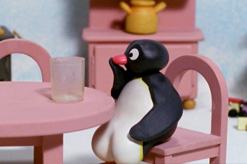 Pingu sitzt am Tisch. – Bild: SRF/​Joker Inc., d.b.a., The Pygos Group