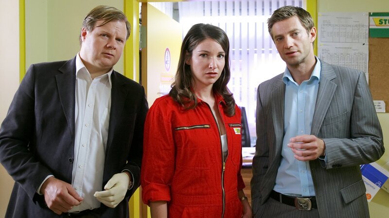 Nachdem Julia Stuller (Sophie Wepper, M.) ihren Vater tot aufgefunden hat, nehmen die Kommissare Hansen (Igor Jeftic, r.) und Hartl (Michael A. Grimm, l.) die Ermittlungen auf. – Bild: ZDF/​Christian A. Rieger