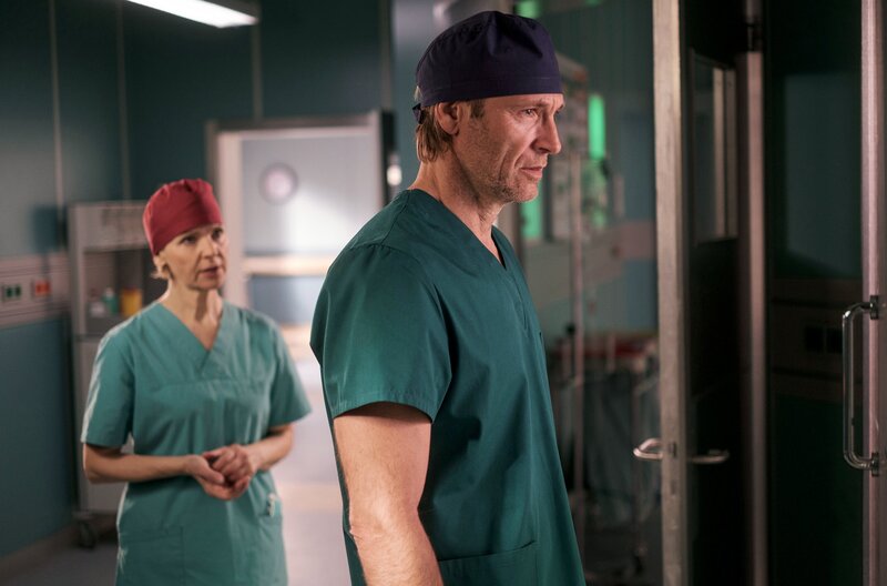 Während seine Tochter operiert wird, steht Dr. Martin Stein (Bernhard Bettermann) ,gelähmt vor Angst und Sorge, vor dem OP. Seine Kollegin und Freundin Dr. Kathrin Globisch (Andrea Kathrin Loewig) versucht ihn abzulenken und zu beruhigen. – Bild: MDR/​Saxonia Media/​Robert Strehler