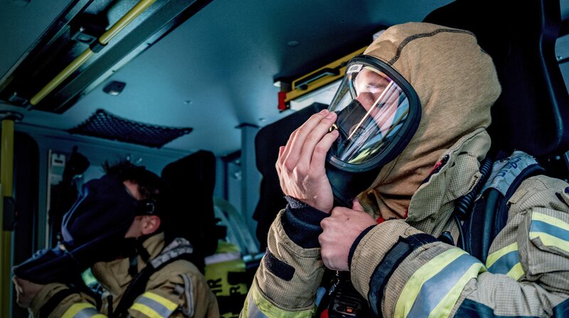 Feuerwehrleute der Berufsfeuerwehr Heidelberg legen eine Atemschutzmaske an. – Bild: SWR/​Sebastian Drolshagen