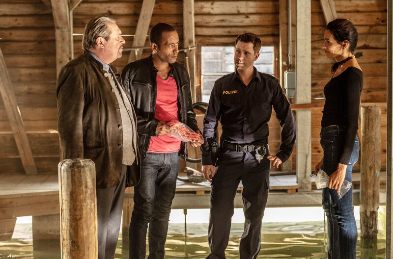 Michael Krohs Boot wurde gefunden und geborgen. Die Crew der Berchtesgadener Polizeistation sichert Beweismaterial und beratschlagt über die weitere Vorgehensweise in diesem Mordfall. V.l.n.r.: Kommissar Benedikt Beissl (Andreas Giebel), Kommissar Jerry Paulsen (Peter Marton), Polizist Max Ruffer (Nepo Fitz) und Pathologin Sonja Bitterling (Genoveva Mayer) – Bild: „Bild: ARD/​Raymond Roemke (S2+). ARD-Programmdirektion/​Bildredaktion