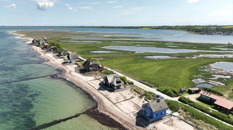 Auf Tuchfühlung mit dem Meer: Die Strandvillen-Eigentümer vom Graswarder leben in ständiger Sorge, dass sich die Ostsee wieder ein Stück Land holt – die Holzbuhnen im Wasser sollen das verhindern. – Bild: NDR/​Johannes Rudolph