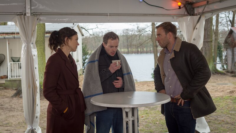 Ausgerechnet Christian Bahlbeck (Michel Diercks, M.) hat seinen Vater im Wasser entdeckt und an Land gezogen. Christian steht unter Schock, doch die Kommissare Pöhlmann (Dominic Boeer, r.) und Joost (Nike Fuhrmann, l.) nehmen die Erstbefragung vor. – Bild: ZDF und Marc Meyerbroeker