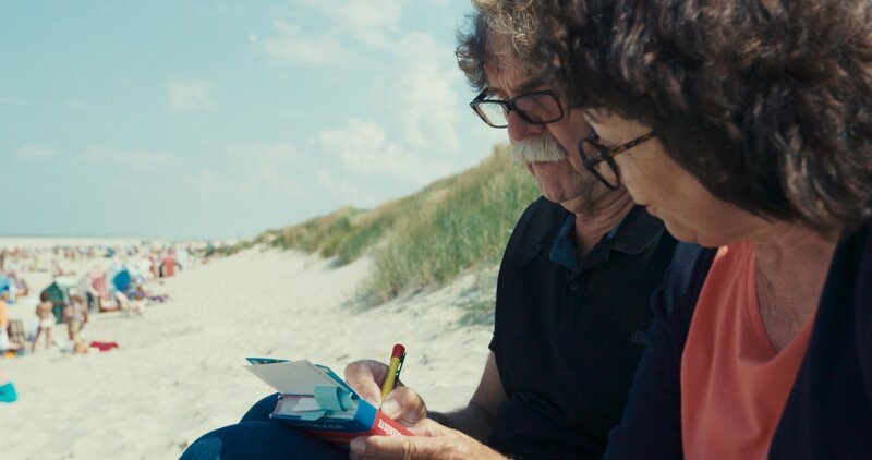 Das Elternpaar Ulla und Didi Högel schreibt eine Postkarte an den Sohn ins Gefängnis. – Bild: ZDF und Tobias Tempel