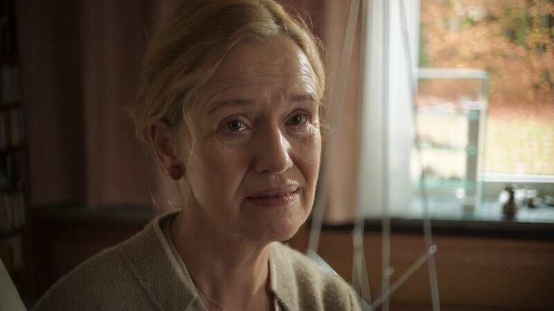 Erika Schönfeld (Marion Reuter) sitzt auf der Sofakante und wird von Kommissar Felix Voss befragt. – Bild: ORF/​BR/​Hager Moss Film/​Daniela Knapp