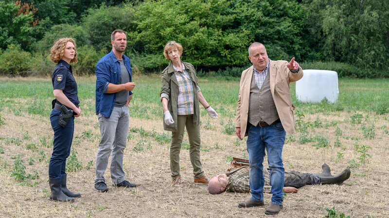 Chefkommissar Reuter (Udo Kroschwald, r.) vermutet gegenüber der Rechtsmedizinerin Dr. Sturbeck (Katharina Blaschke, 3.v.r.) und den Kommissaren Pöhlmann (Dominic Boeer, 2.v.l.) und Moorkamp (Stella Hinrichs, l.), dass der Landwirt Thiess Passow (Harald Krull, 2.v.r.) von seinem eigenen Traktor überfahren wurde. – Bild: ZDF /​ Meyerbroeker