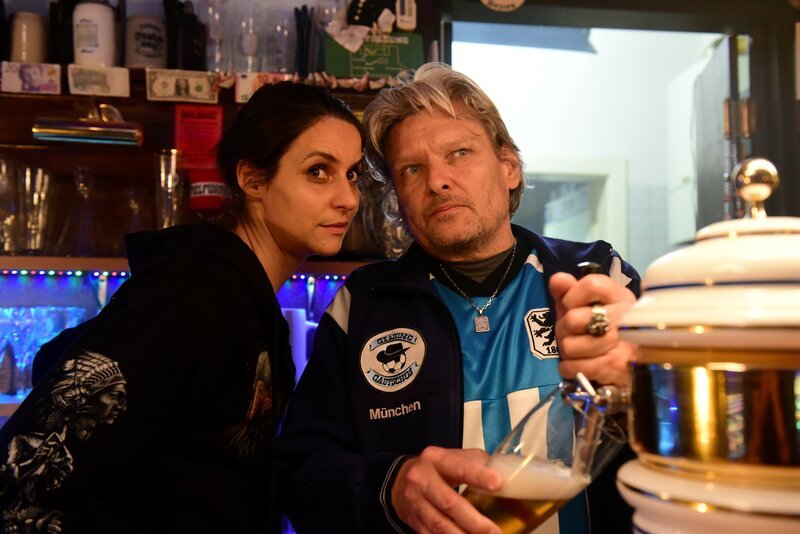 Anke (Liane Forestieri) schützt ihren Chef Armin (Ernst Hannawald) vom Kronenstüberl vor den zu neugierigen Fragen der Kommissare. – Bild: ZDF/​Jürgen Olczyk