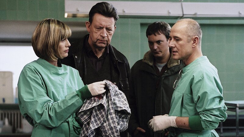 Dr. Robert Kolmaar (Ulrich Mühe, r.), Dr. Judith Sommer (Gesine Cukrowski, l.), Kommissar Joe Hoffer (Jörg Gudzuhn, 2.v.l.) und sein Assistent Etzel Hanisch (Daniel Krauss, 2.v.r.) untersuchen die Kleidung des ermordeten Jungen. – Bild: ZDF