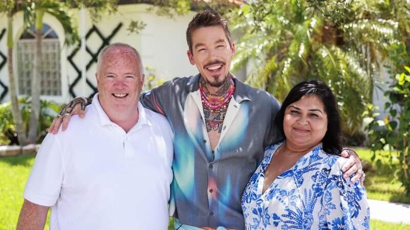 From left to right: Robert Douglas, Host David Bromstad, and Swati Dave pose for a picture outside of House 1, Dahoon Drive, as seen on My Lottery Dream Home, Season 17. – Bild: Warner Bros. Discovery