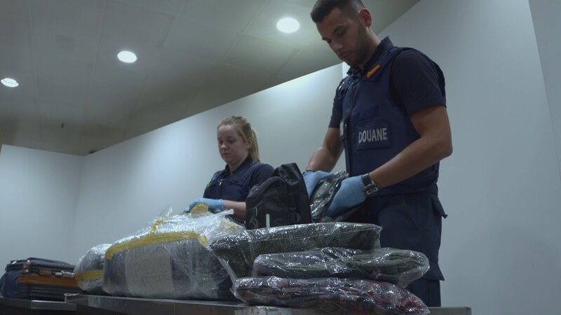 Die Grenzbeamten durchsuchen den Koffer. – Bild: Discovery Communications