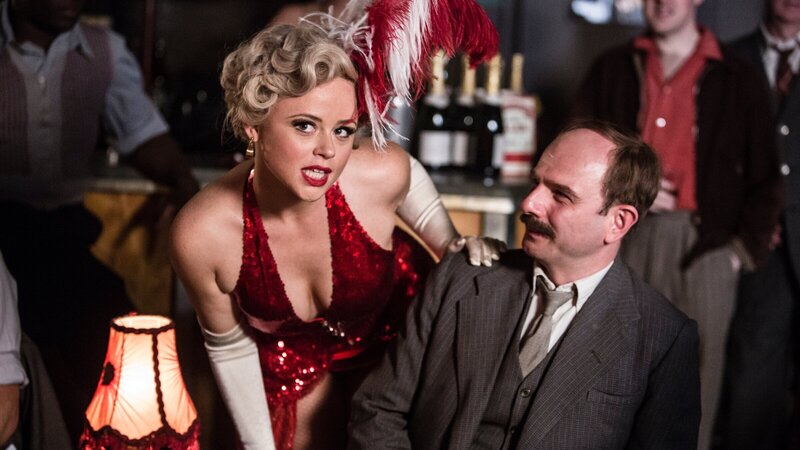 Fifi Caviara (Emily Atack), die Mitarbeiterin in dem Burlesque-Club in Kembleford, heißt Inspector Mallory (Jack Deam) willkommen. Der Polizist genießt den Anblick der attraktiven Frauen, obwohl er gleichzeitig hofft, nicht in diesem Etablissement entdeckt zu werden. – Bild: ZDF und Gary Moyes
