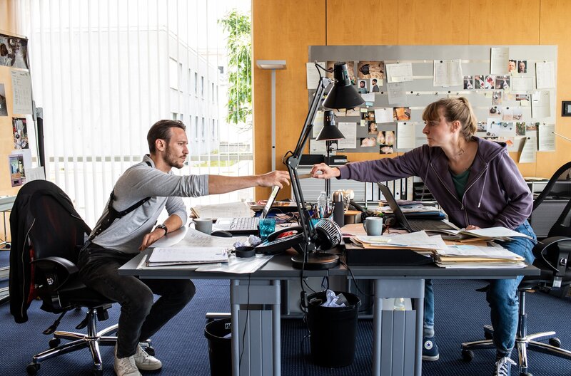 Pia Heinrich (Ines Marie Westernströer) und Leo Hölzer (Vladimir Burlakov) tauschen sich im Kommissariat über ein Foto aus – ein entscheidender Hinweis? – Bild: SR/​Manuela Meyer