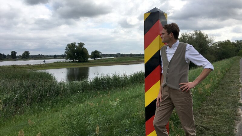 Die große Doku-Reihe lädt dazu ein, auf Fontanes Spuren die Geschichte der Region Berlin-Brandenburg lustvoll neu zu erkunden. Die fünf Bände seiner „Wanderungen durch die Mark Brandenburg“ geben dabei die Route vor. Teil 2, wieder präsentiert von Fabian Hinrichs, führt die Zuschauer in „Fontanes Oderland“, damals noch mitten in Preußen , heute die Grenzregion zwischen Deutschland und Polen. – Fabian Hinrichs auf Fontanes Spuren an der Oder mit Blick nach Polen – Bild: rbb/​Johannes Unger