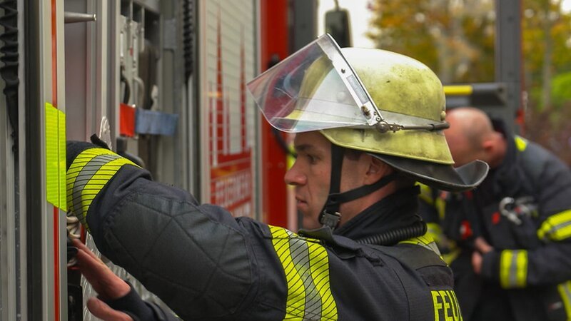 A firefighter from Mainz packs a tool into the fire truck. – Bild: Warner Bros. Discovery