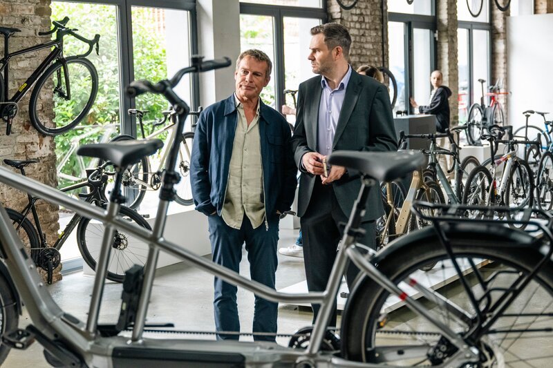 Die Kommissare Jonas Fischer (Jonas Piloty, r.) und Matti Wagner (Pierre Besson, l.) besuchen den Fahrradladen, in dem die tote Influencerin kurz vor ihrem Tod ein „Meet and Greet“ veranstaltete. – Bild: ZDF und Martin Rottenkolber
