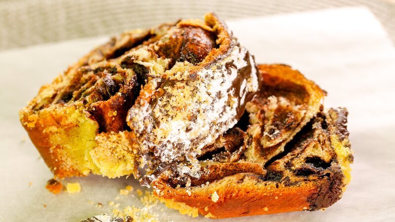 Schokoladen-Babka ist ein süßes, butterartiges Brot im Brioche-Stil, gefüllt mit Strudeln aus gesüßter dunkler Schokolade und Schokoladenstückchen, bedeckt mit Streuseln und Schokolade bei „Isaac’s Bakery“ in Brooklyn. – Bild: ORF/​Warner/​The Travel Channel