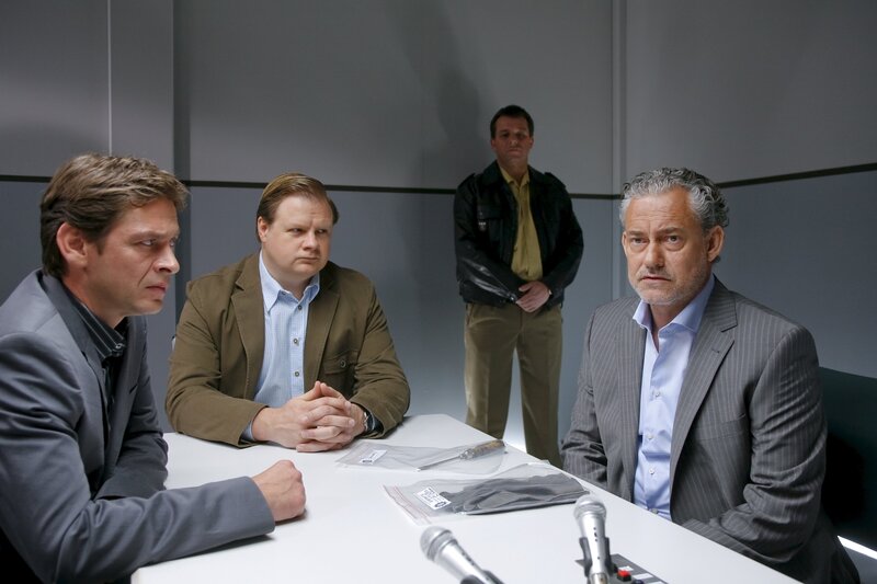 Die Cops Christian Lind (Tom Mikulla, l.), Tobias Hartl (Michael A. Grimm, 2.v.l.) zweifeln an der Glaubwürdigkeit des EU-Abgeordneten Eckart König (Rolf Kanies, r.). Polizist im Hintergrund: Komparse. – Bild: ZDF/​Christian A. Rieger