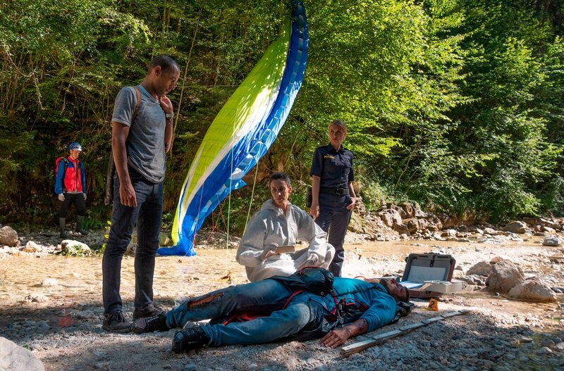 Der Profi-Paraglider Mike Bischoff ist in den Tod gestürzt. War es kein Unfall? Die Ermittlungen der Kommissare bestätigen zunehmend diese These. V.l.n.r. Jerry Paulsen (Peter Marton), Pathologin Sonja Bitterling (Genoveva Mayer), Caro Reiser (Sarah Thonig) und Komparsen. – Bild: BR/​ARD/​Lucky Bird Pictures/​Angela Schablitz