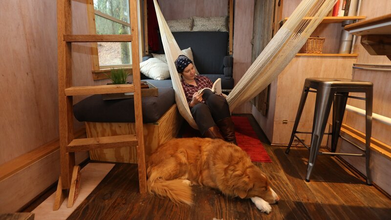 After completing her tiny house, builder, Sophie Clark, takes a moment to relax with a book in her hammock, with her faithful companion Whisky at her feet, in Seattle, Washington, as seen on Tiny House, Big Living. – Bild: HGTV