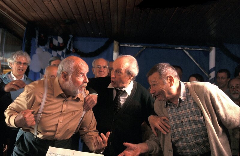 Während der Probe des Volkschors Almenrausch kommt es in der Kneipe zum Krach: Chorleiter Karl Worschak (Ernst Stankovski) versucht, die Streithähne Freiberger (Erich Hallhuber sen., rechts) und Beimlein (Wolfgang Freundorfer, links) zu beruhigen. – Bild: BR/​Bavaria Film GmbH/​Manfred Lämmerer