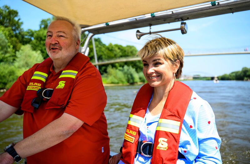 Moderatorin Sabine Heinrich (r) reist einmal schräg durch NRW und trifft in Minden Volker Zoerb von der DLRG, der sie mit auf Weser-Kontrollfahrt nimmt. – Bild: WDR/​Julia Feldhagen