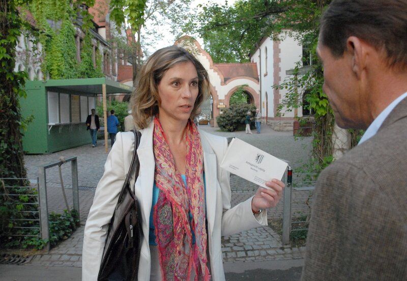 ARD TIERÄRZTIN DR. MERTENS IV. Staffel mit 13 neuen Folgen, Folge 49, „Falscher Verdacht“. Es wird ernst. Staatsanwältin Dr. Kristina Winter (Carin C. Tietze, l.) überreicht Zoodirektor Dr. Fährmann (Michael Lesch, l.) den Durchsuchungsbeschluß für seine Privatwohnung. Der Verdacht der Spendenveruntreuung lastet schwer auf ihm. – Bild: ARD/​Christa Köfer