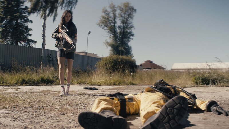 Evelin (Emily Kusche) wagt sich nur mit der Waffe in der Hand an den gelben Mann heran. – Bild: Syrreal Entertainment /​ Christian Alvart