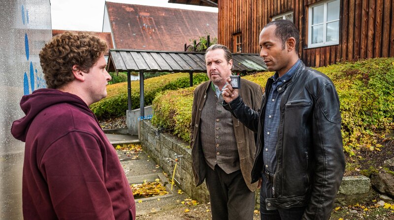 Die Kommissare Benedikt Beissl (Andreas Giebel, M.) und Jerry Paulsen (Peter Marton, r.) befragen den Wäschefahrer (David Lindermeier, l.) zum aktuellen Mordfall. – Bild: ARD/​BR/​Lucky Bird Pictures/​Andreas Steffan/​Andreas Steffan